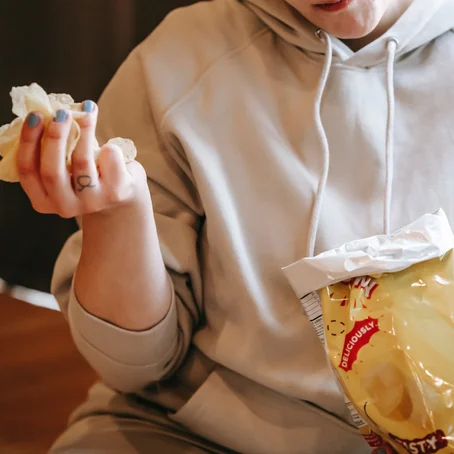 Vrouw eet chips uit zak