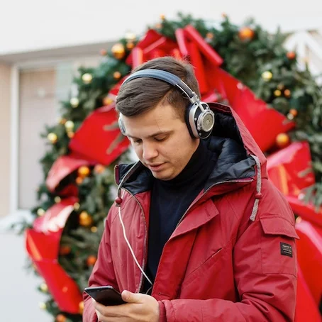 Man met koptelefoon staat voor een kerstkrans